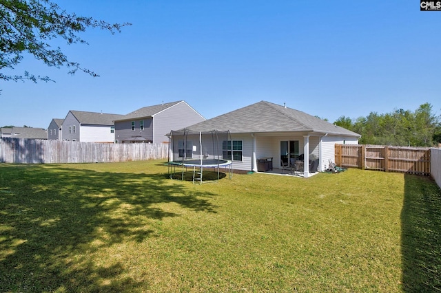 back of property featuring a lawn, a trampoline, a fenced backyard, and a patio
