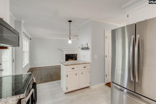 kitchen with stainless steel appliances, ornamental molding, and white cabinetry