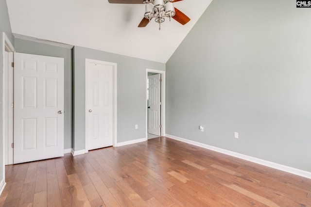 unfurnished bedroom featuring baseboards, ceiling fan, high vaulted ceiling, and wood finished floors