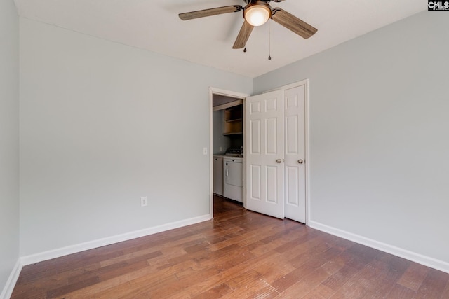 unfurnished bedroom featuring separate washer and dryer, baseboards, ceiling fan, and wood finished floors