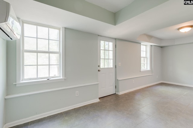 interior space featuring baseboards, a wall unit AC, and a raised ceiling