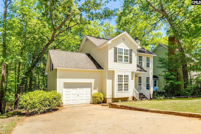 traditional home featuring roof with shingles, an attached garage, concrete driveway, and a front lawn