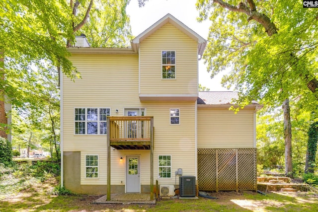 rear view of house with ac unit, a chimney, and cooling unit