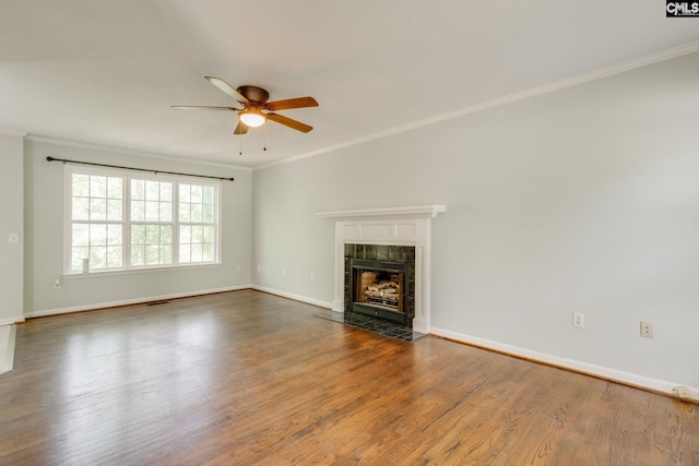 unfurnished living room with crown molding, dark wood-style flooring, ceiling fan, a fireplace, and baseboards