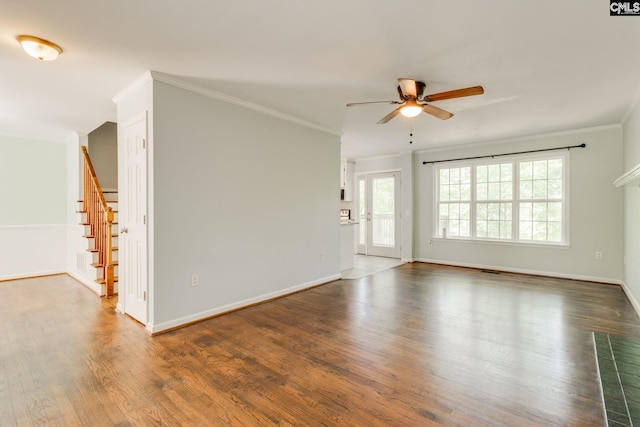 unfurnished room with ornamental molding, wood finished floors, baseboards, ceiling fan, and stairway
