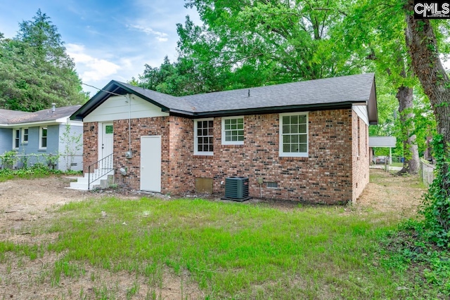rear view of property featuring fence, brick siding, crawl space, entry steps, and central air condition unit