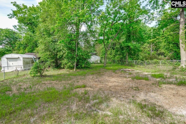 view of yard featuring an outdoor structure, a garage, and fence