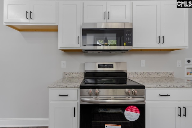 kitchen with light stone counters, appliances with stainless steel finishes, and white cabinets