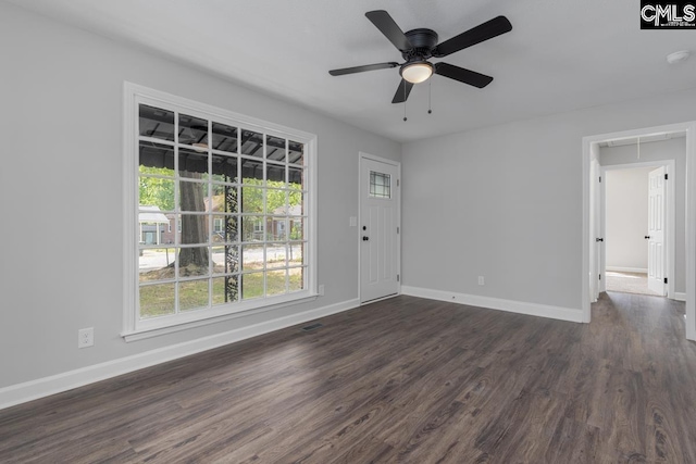 empty room featuring baseboards, ceiling fan, attic access, and dark wood-style floors