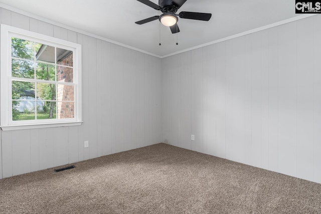 carpeted empty room with visible vents, ornamental molding, and ceiling fan