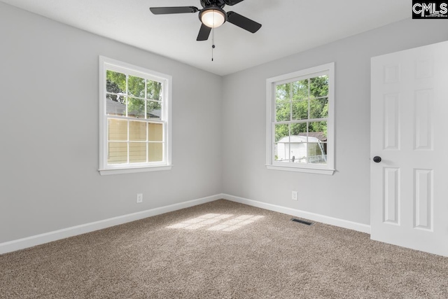 carpeted spare room featuring baseboards, a ceiling fan, and visible vents