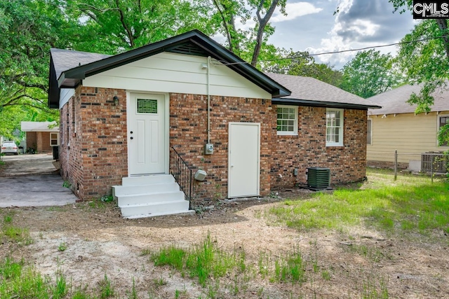 back of house featuring brick siding, cooling unit, fence, and entry steps