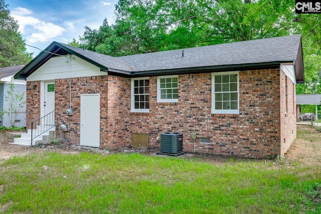 view of front of property with roof with shingles, entry steps, central AC, and brick siding