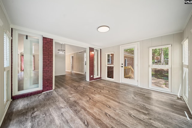unfurnished room with ornamental molding and wood finished floors