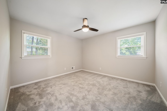 empty room featuring carpet flooring, ceiling fan, baseboards, and a wealth of natural light