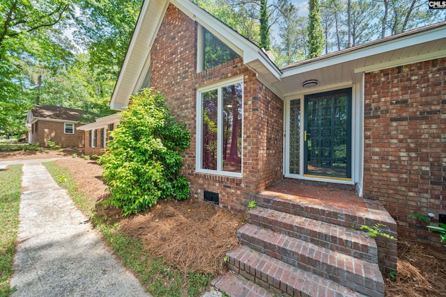 property entrance featuring brick siding and crawl space