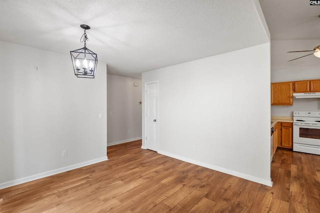 unfurnished dining area featuring light wood-style floors, baseboards, a textured ceiling, and a chandelier