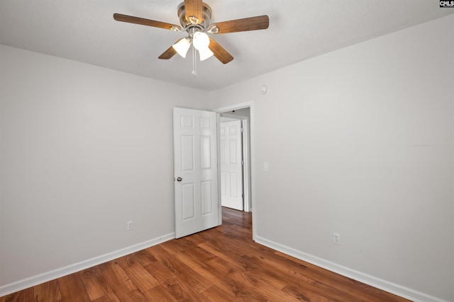 spare room with baseboards, ceiling fan, and wood finished floors
