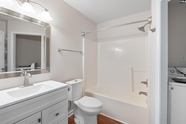 bathroom featuring vanity, tub / shower combination, wood finished floors, toilet, and washer / clothes dryer