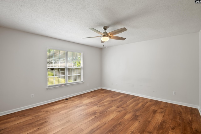 unfurnished room with baseboards, a ceiling fan, a textured ceiling, and wood finished floors