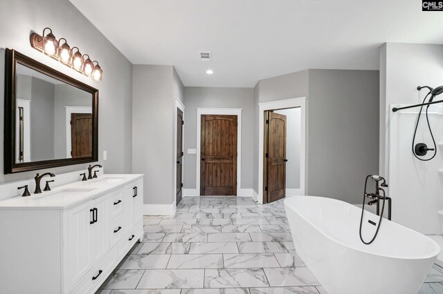 bathroom with visible vents, marble finish floor, a freestanding tub, recessed lighting, and a sink