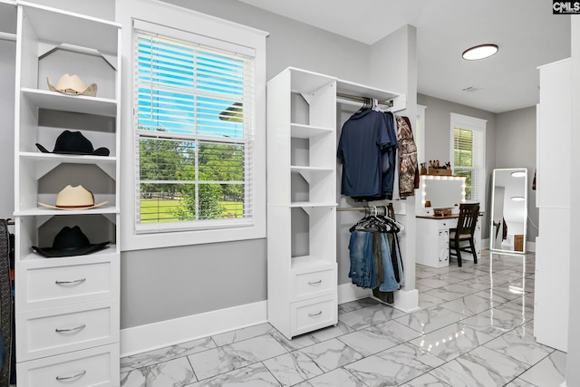 walk in closet featuring marble finish floor