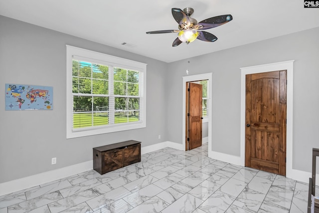 spare room featuring baseboards, ceiling fan, a wealth of natural light, and marble finish floor