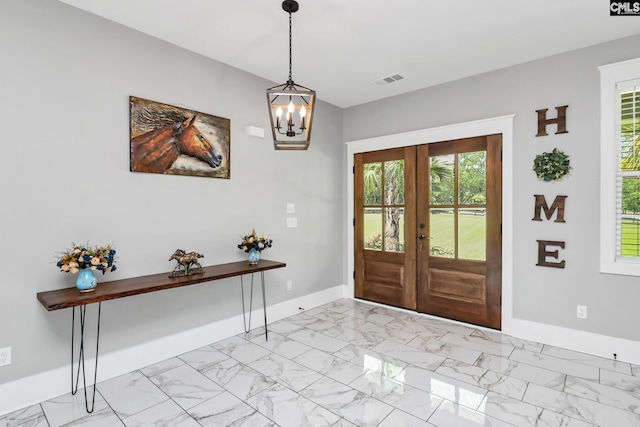 foyer entrance featuring marble finish floor, a chandelier, french doors, and baseboards