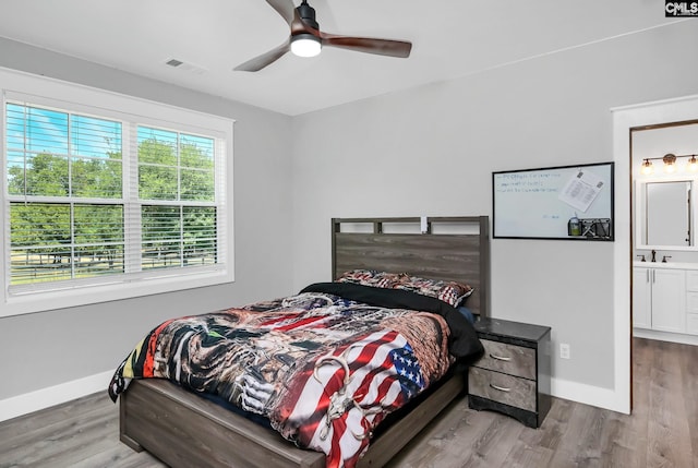 bedroom featuring a sink, baseboards, wood finished floors, and visible vents