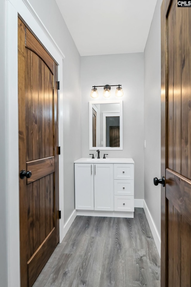 bathroom with baseboards, wood finished floors, and vanity