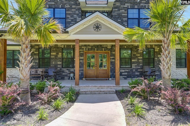 doorway to property with covered porch, french doors, and stone siding