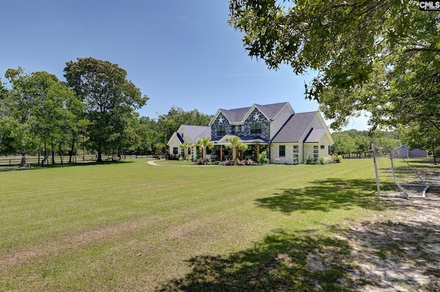 view of front of home featuring a front yard, stone siding, and fence