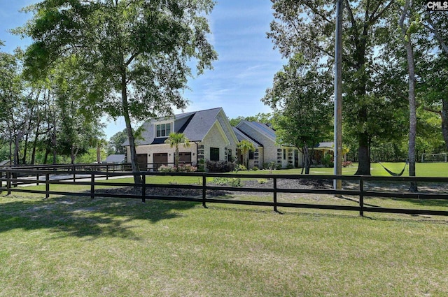 exterior space with a yard, stone siding, an attached garage, and fence