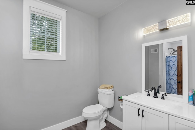 bathroom featuring toilet, wood finished floors, vanity, visible vents, and baseboards