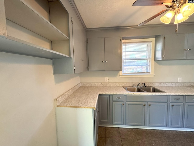 kitchen featuring light countertops, a sink, dark tile patterned flooring, and ornamental molding