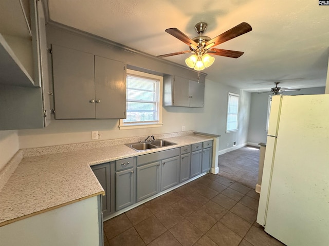 kitchen featuring freestanding refrigerator, a ceiling fan, gray cabinetry, and a sink