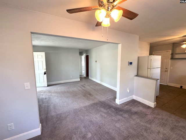 unfurnished room featuring baseboards, a ceiling fan, and dark carpet