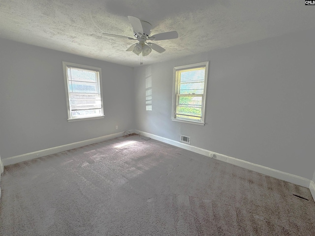 carpeted empty room featuring visible vents, a ceiling fan, a textured ceiling, and baseboards