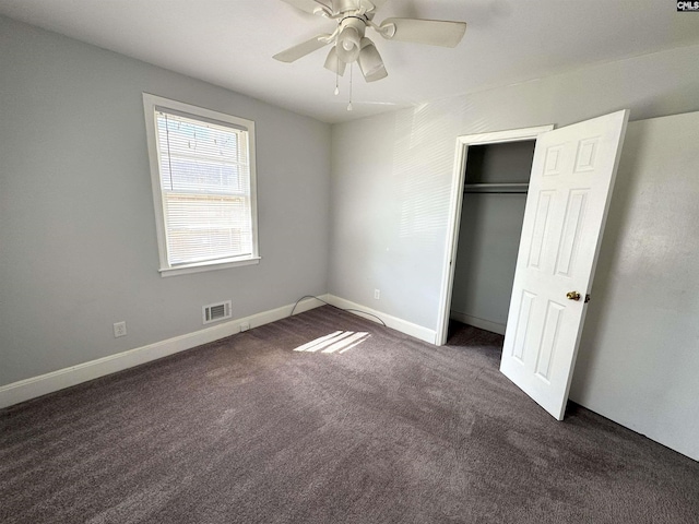 unfurnished bedroom featuring visible vents, a closet, baseboards, dark carpet, and a ceiling fan
