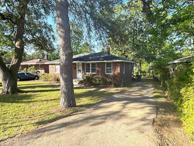 single story home with brick siding, driveway, a chimney, and a front lawn