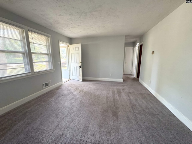 empty room with carpet floors, baseboards, a textured ceiling, and visible vents