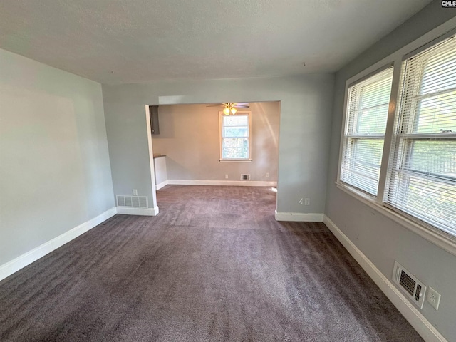 unfurnished room featuring baseboards, ceiling fan, dark colored carpet, and visible vents