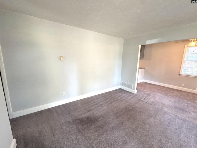 unfurnished room with visible vents, a ceiling fan, baseboards, and dark colored carpet