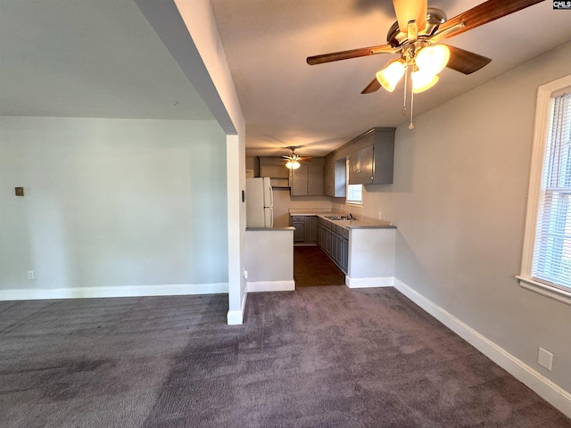 kitchen featuring baseboards, freestanding refrigerator, a ceiling fan, and dark colored carpet