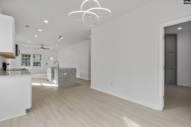 unfurnished living room with baseboards, light wood-type flooring, recessed lighting, a sink, and ceiling fan with notable chandelier