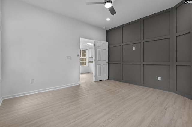 unfurnished bedroom with ceiling fan, a decorative wall, light wood-style flooring, recessed lighting, and baseboards