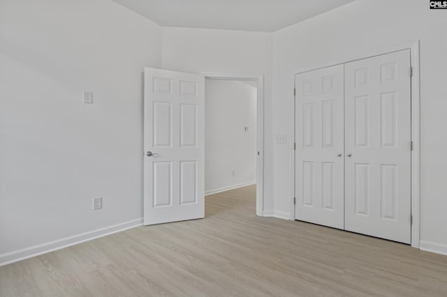 unfurnished bedroom with light wood-style floors, baseboards, and a closet