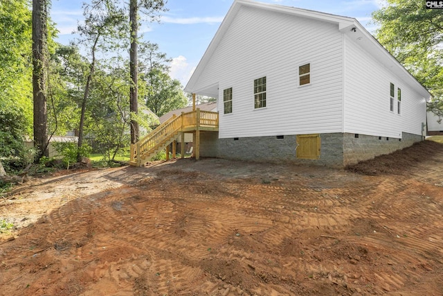 back of property featuring crawl space, a wooden deck, and stairs