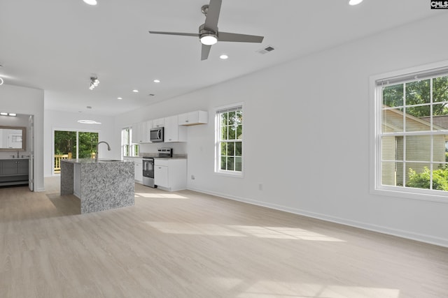 unfurnished living room with visible vents, a healthy amount of sunlight, and light wood-style flooring