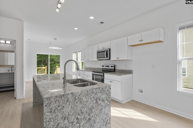 kitchen with light wood-type flooring, a sink, light stone counters, white cabinets, and stainless steel appliances